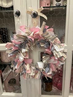 a wreath is hanging on the front door with ribbon and ribbons attached to it's sides