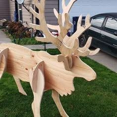 a wooden sculpture of a deer with antlers on it's back legs in front of a house