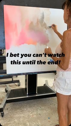 a woman is painting on a large sign with words that read, i bet you can't watch this until the end