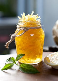 a glass jar filled with honey sitting on top of a table next to lemon slices