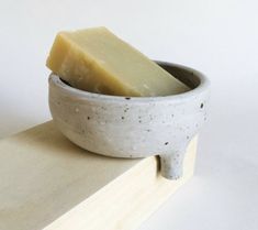 a white bowl with a piece of cheese in it on top of a wooden block