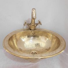 an ornate gold sink on display against a white background