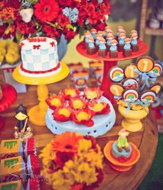 a table topped with lots of colorful cakes and cupcakes on top of it