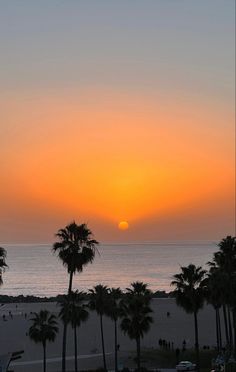 the sun is setting over the beach with palm trees