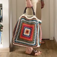 a woman holding a crocheted bag in her hands