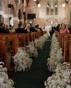 people sitting in pews at a church with white flowers on the floor and green carpet