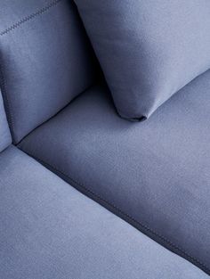 a close up view of a blue couch with two pillows on it's back