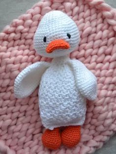 a knitted ducky doll sitting on top of a pink blanket in the shape of a ball