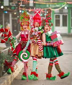 three women dressed up in christmas themed costumes and holding candy canes while standing next to each other