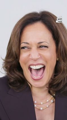 a woman with her mouth open and wearing a black blazer smiling at the camera