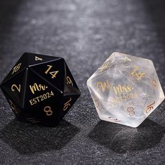 two black and gold dices sitting on top of a gray table next to each other