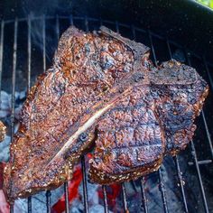 two steaks are cooking on the grill