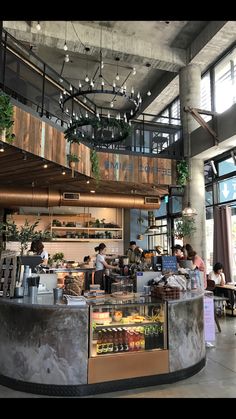 the inside of a restaurant with people sitting at tables and hanging plants on the ceiling