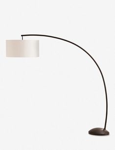 a black floor lamp with a white shade on it's side and a round base