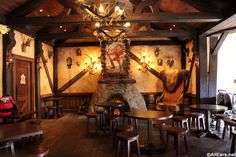 a restaurant with wooden tables and chairs around a fire place in the middle of the room