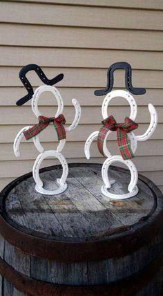 two snowmen made out of horseshoes sitting on top of a barrel