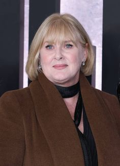 a woman with blonde hair wearing a brown coat