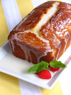 a loaf of pound cake on a plate with raspberries and mint sprig