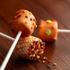 two cake pops with sprinkles on them sitting on a table next to each other