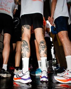 several people with tattoos on their legs standing in front of each other and holding hands