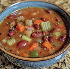 a bowl of soup with beans, carrots and celery on a table