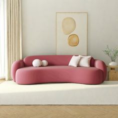 a pink couch sitting on top of a hard wood floor next to a white wall