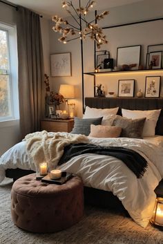 a bedroom with a large bed covered in blankets and pillows, candles on the floor