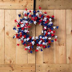 a red, white and blue wreath hanging on a wooden door