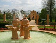 there are two statues in the fountain with water coming out of their heads and hands