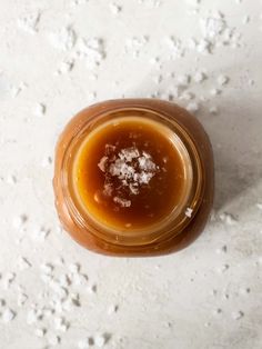 a jar filled with liquid sitting on top of a white tablecloth covered in snow