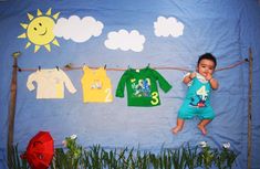 a baby is hanging out on a clothes line with three shirts and two umbrellas