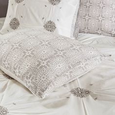 a bed with white sheets and pillows on top of it