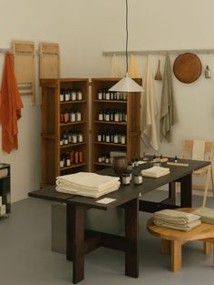 a room with many items on the table and hanging lights above it, along with several wooden shelves