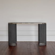 a black and gold console table in an empty room with hard wood flooring on the side