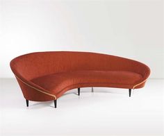 an orange curved couch sitting on top of a white floor