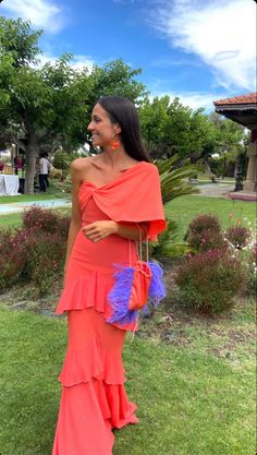 a woman in an orange dress is standing on the grass