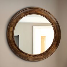 a round mirror hanging on the wall above a sink in a room with white walls