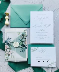 the wedding stationery is laid out on top of an envelope and some green paper