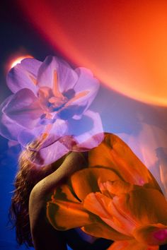 a woman with flowers on her head in front of a blue and orange background,