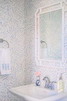 a white sink sitting under a bathroom mirror next to a wall mounted soap dispenser