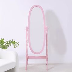 a pink vanity mirror sitting on top of a white chair next to a potted plant