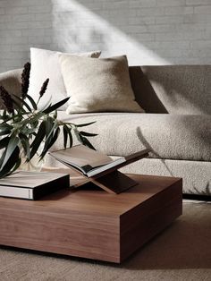 a coffee table with a book on it in front of a couch and pillows,