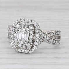 a white gold diamond ring with an intricate design on the band and center surrounded by round brilliant cut diamonds