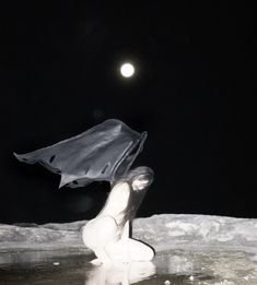 a woman sitting on the moon holding an umbrella