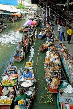 many boats are lined up along the water with food on them and people walking around