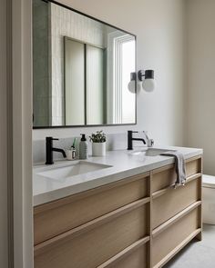 a bathroom with two sinks and a large mirror above the vanity area is seen in this image