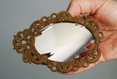 a hand holding a small mirror in it's left side with an intricate design