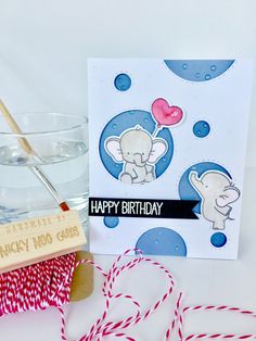 an elephant birthday card next to a glass of water and some twine on the table