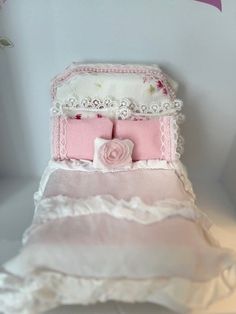 a pink and white bed sitting on top of a table next to a flower vase