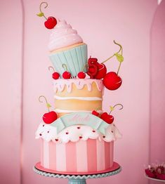 a three tiered cake with cherries and cupcakes on top